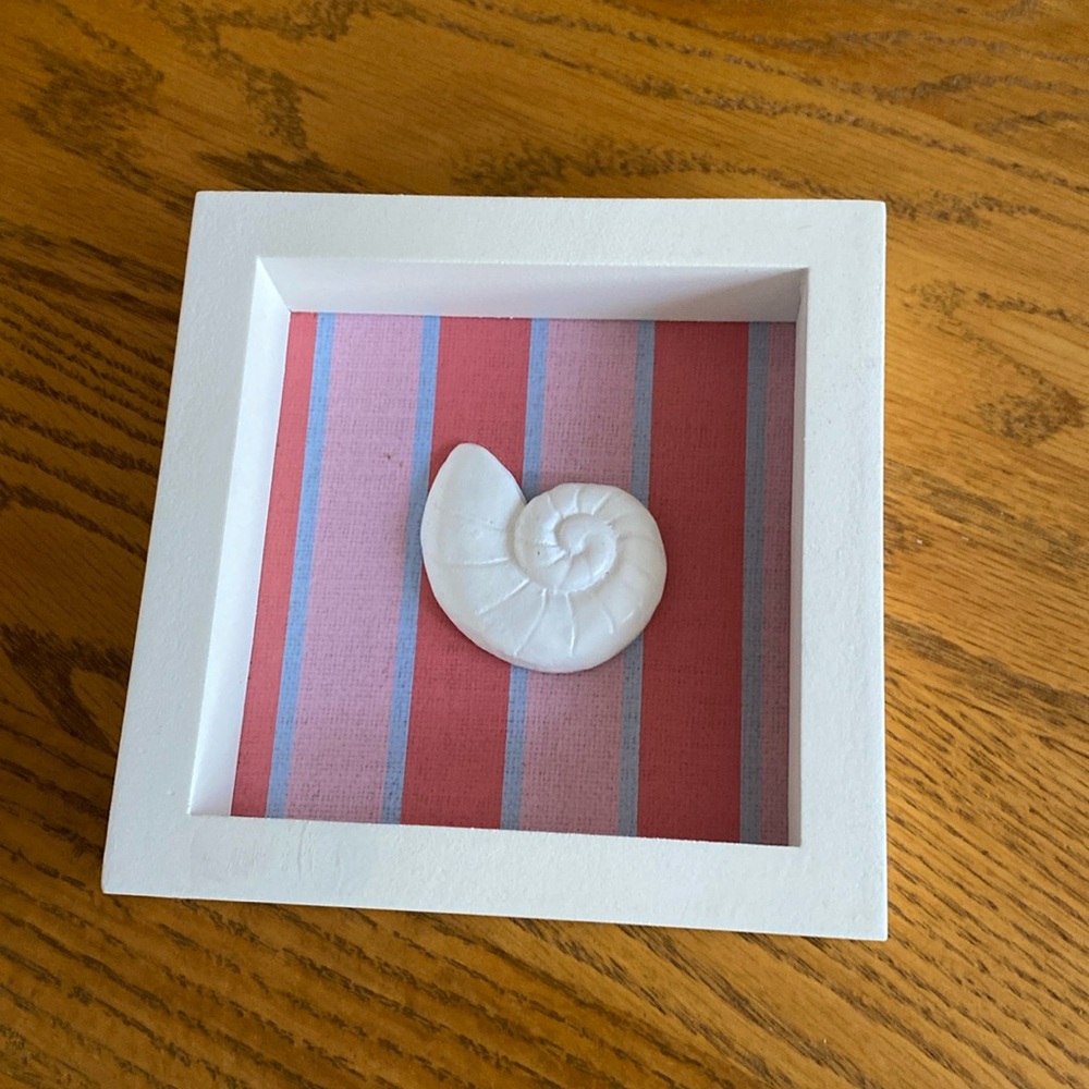 Cute framed picture of a shell for that beach house esthetic.